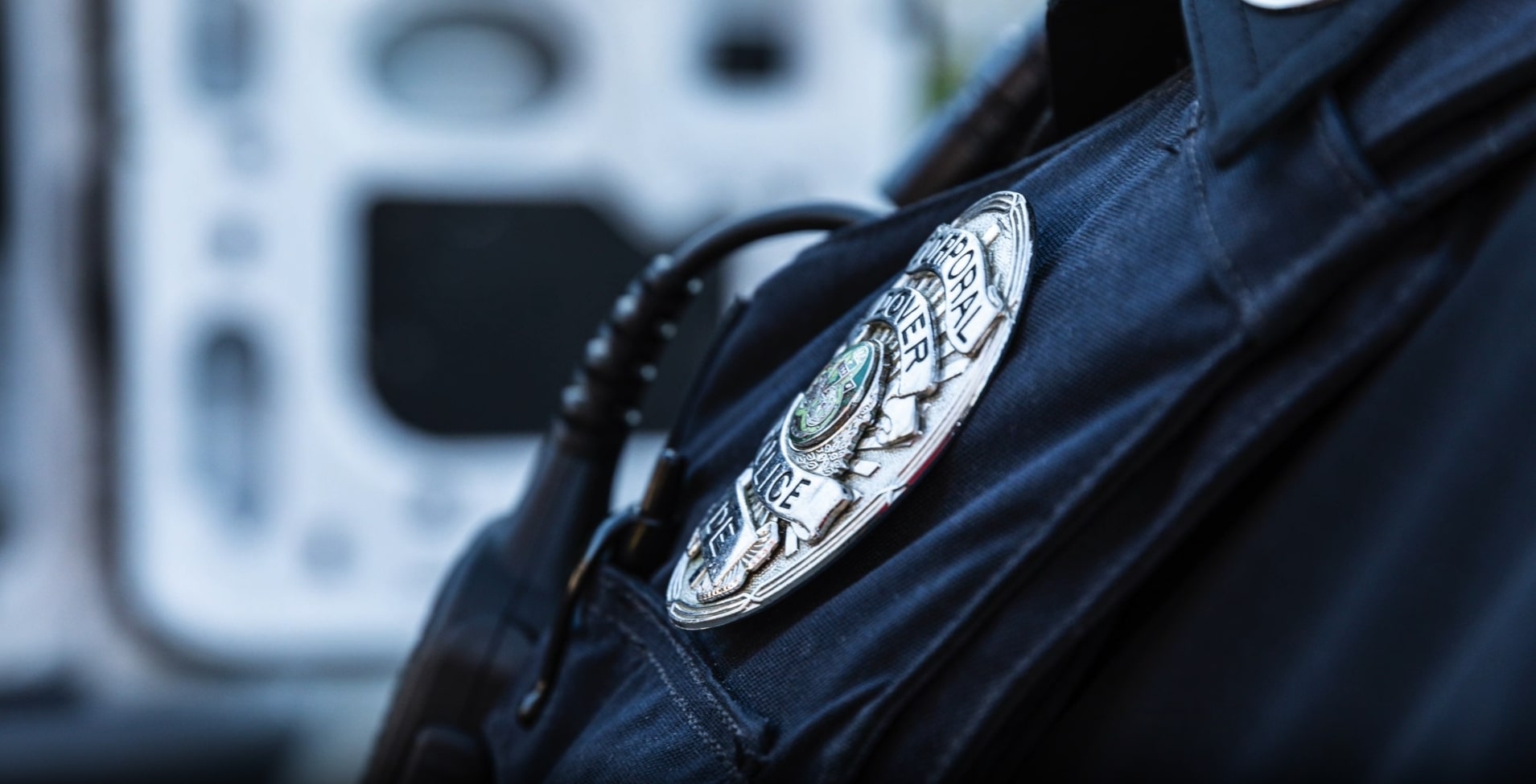 Close view of a uniformed officer's badge and radio